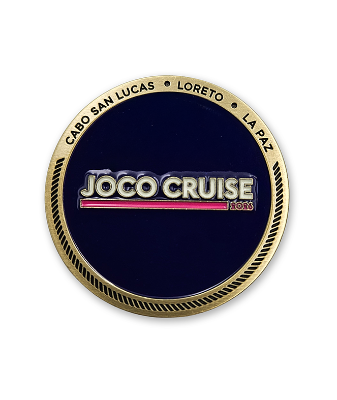 Circular gold coin with a dark violet enamel filling the center. Text of the top is engraved, "CABO SAN LUCAS LORETO LA PA6" and the JOCO CRUISE 2026 logo is in the middle in white and pink.
