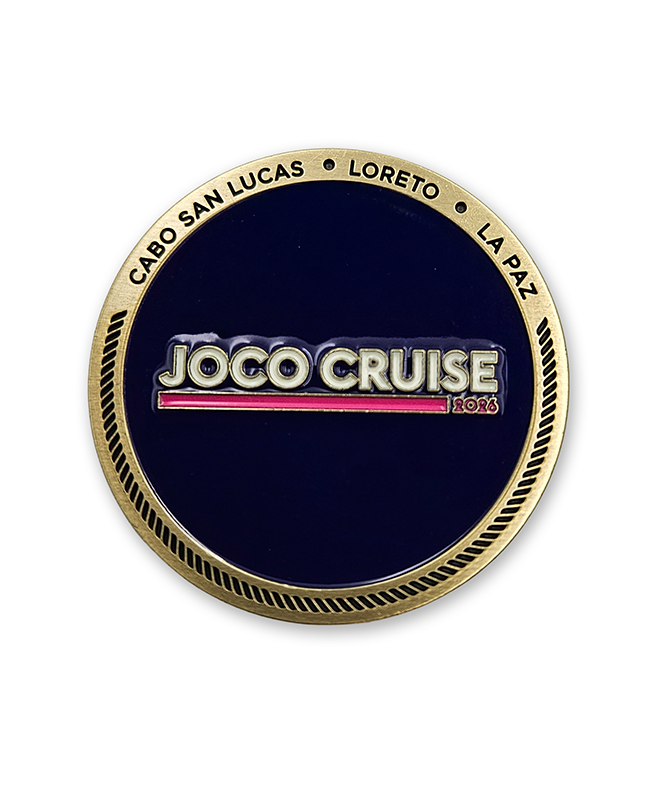 Circular gold coin with a dark violet enamel filling the center. Text of the top is engraved, "CABO SAN LUCAS LORETO LA PA6" and the JOCO CRUISE 2026 logo is in the middle in white and pink.