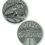 A digital mockup of a dark silver coin. The front shows an image of a bus with the text "One DBloon; Agimus Liberos Adjutum" The back shows an image of a road and tree-shaped air freshener with the text "Desert Bus for Hope 2023"