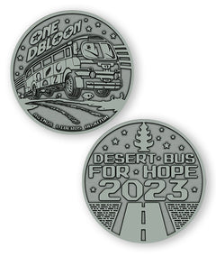 A digital mockup of a dark silver coin. The front shows an image of a bus with the text "One DBloon; Agimus Liberos Adjutum" The back shows an image of a road and tree-shaped air freshener with the text "Desert Bus for Hope 2023"