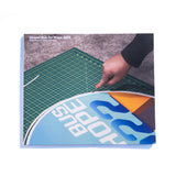 A photo of the front of the Desert Bus for Hope 2022 photo book. It features a hand trimming the margin off of a Desert Bus for Hope 2022 sign.