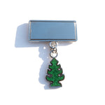 Photo of a pin with a mirrored surface and dangling glittery air freshener shaped charm