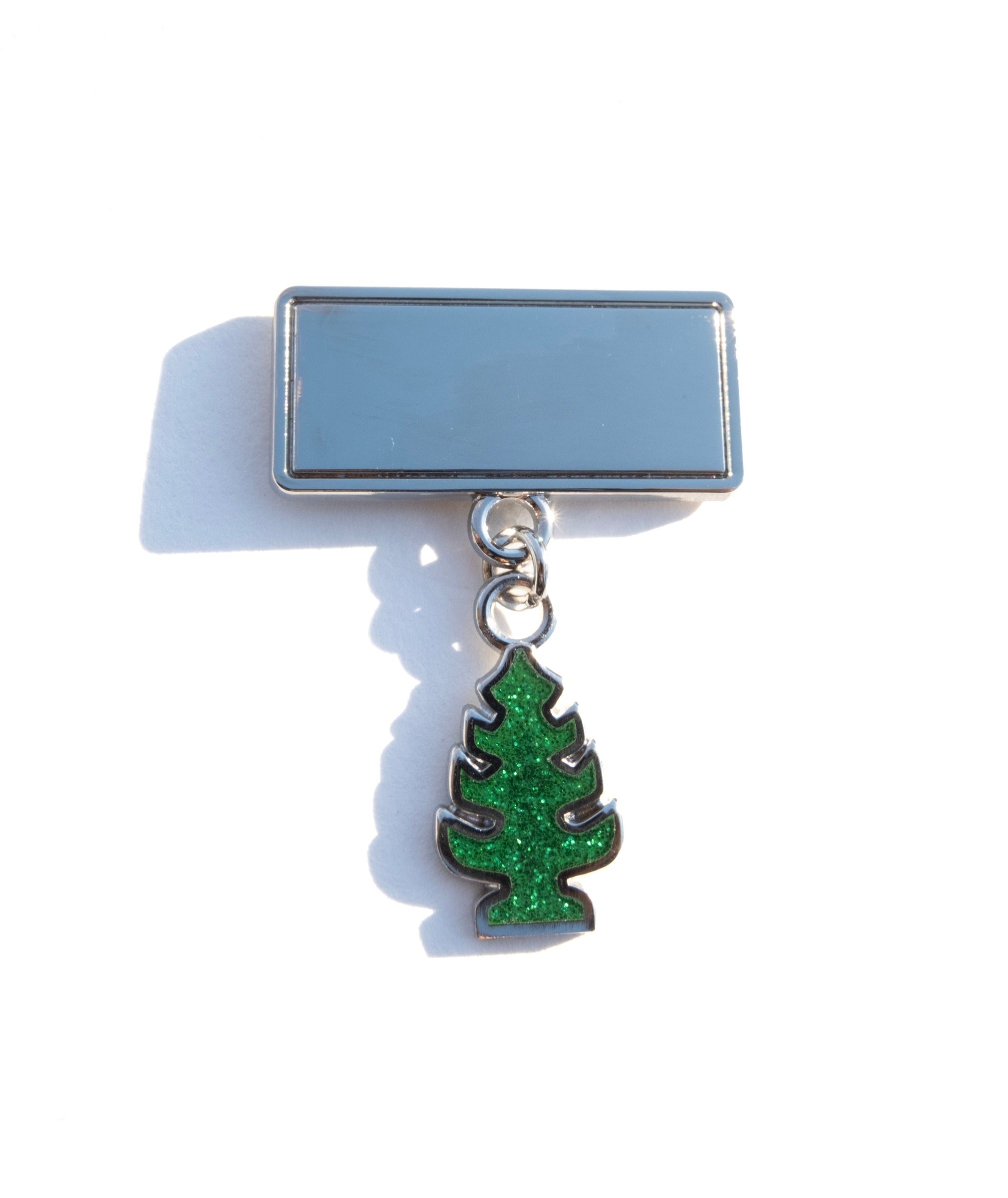 Photo of a pin with a mirrored surface and dangling glittery air freshener shaped charm