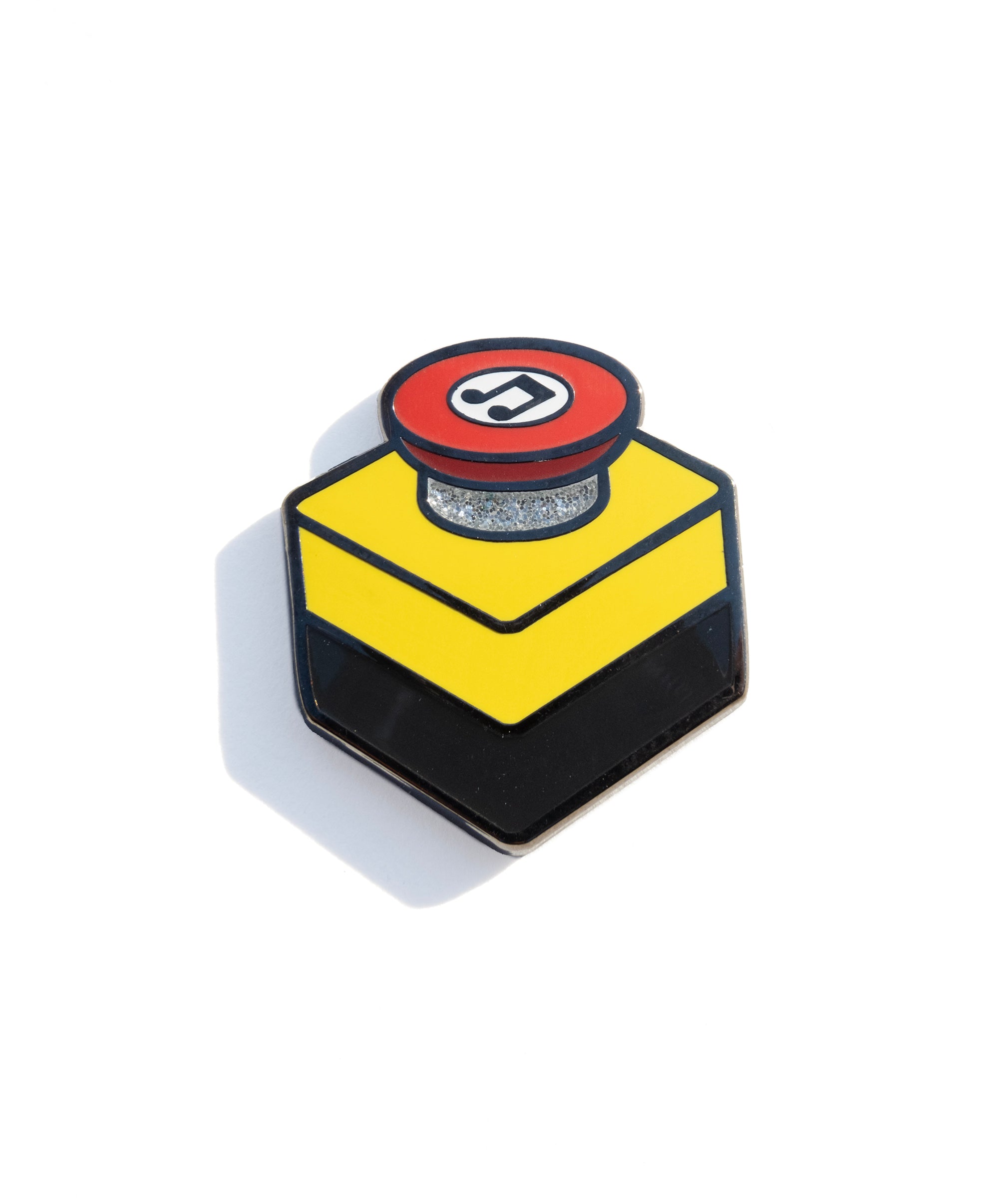 A photo of an enamel pin designed to resemble an emergency stop button. 