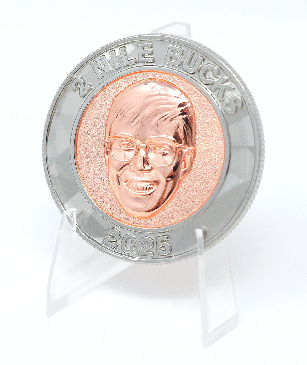 A photo showing a coin on a plastic stand. It has an image of Nigel from NileRed and the text "2 Nile Bucks; 2025" with a diamond fractal pattern.