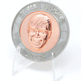 A photo showing a coin on a plastic stand. It has an image of Nigel from NileRed and the text "2 Nile Bucks; 2025" with a diamond fractal pattern.