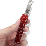 A hand holding an open red bottle opener