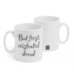 Two white mugs sitting next to each other showing two sides of the same mug. The front side has text that reads "But first existential dread" is decorative lettering. On the back of the mug is a small black square with the words "Semi Rad".