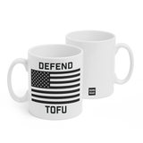 Two white mugs sitting next to each other showing two sides of the same mug. The front side has text that reads "Defend; Tofu" with a black and white American flag in the center. On the back of the mug is a small black square with the words "Semi Rad".