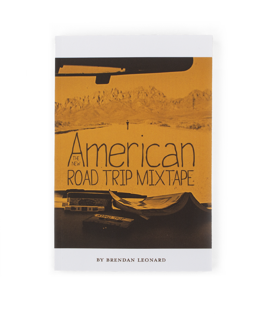 The cover of a book shows a sepia image of a car dashboard and a desert landscape with a man walking down the road. The title reads "The New American Road Trip Mixtape" by Brendan Leonard. From Semi Rad. 