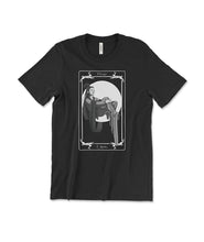 A black t-shirt with a rectangular tarot card on the front with text that reads "Change" on the top and "Spirits" on the bottom. There is a large white circle behind a person sitting down with flowing clothes. 