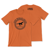 An orange t-shirt that has The Newest Olympian logo on the back neck area and a circular design on the front of a running horse with test that reads "Camp Regular Person; Regular Long Island; Regular New York".   