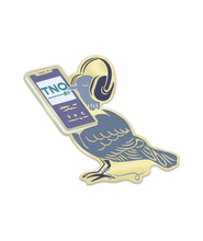 An enamel pin shaped like a blue bird wearing headphones, holding a cellphone that is playing TNO. 
