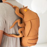 Side view of man wearing cicada shell shaped backpack.