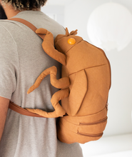 Side view of man wearing cicada shell shaped backpack.