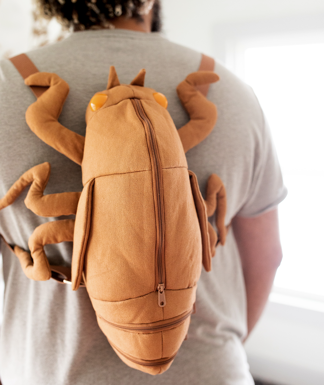 Man wearing cicada shell shaped backpack.
