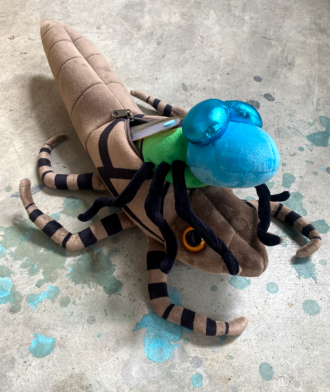 Bright blue dragonfly plush emerging from its larve taupe colored plush shell.