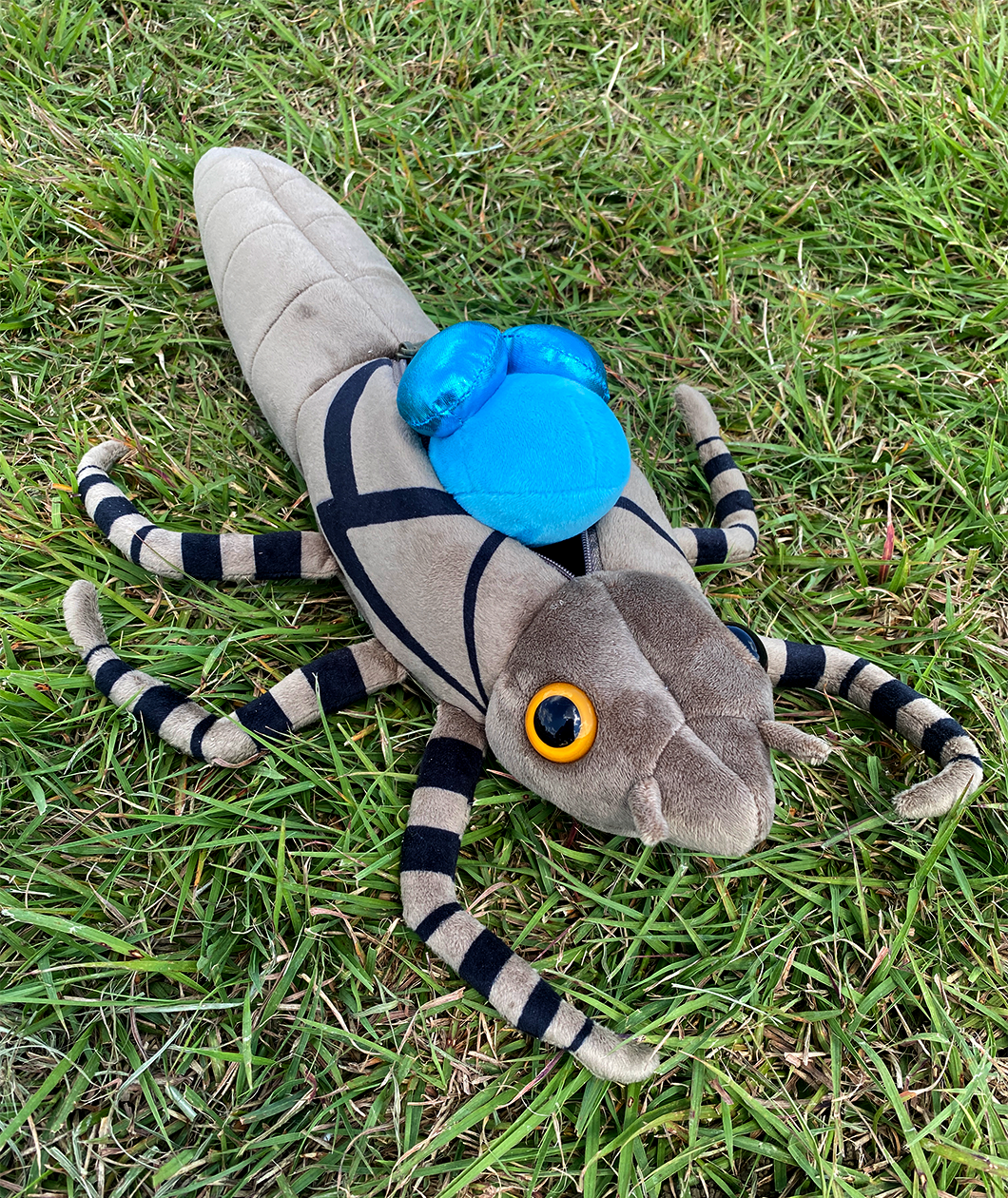 Bright blue dragonfly plush emerging from its larve taupe colored plush shell.