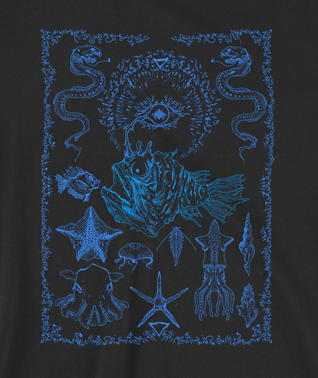 Close up illustration of image on shirt which is blue line art ocean creatures. In the center is an anglerfish with a third eye where its glowing antenna should be. Eels frame the top of the image on each side and then there are fish and squids below. The whole drawing is surrounded by a line art border of squiggles.