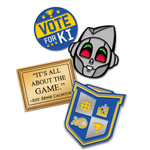 Blue metal circular pin with the words "VOtE FOR KI" with yellow stars. Black Metal pin of a grey robot smiling with red and green eyes. Gold metal rectangular pin that resembles a plaque that says, "IT'S ALL ABOUT THE GAME. ~SGT. ERNIE CALHOUN". And a silver metal pin in the shape of a shield to resemble the VGHS Crest with it's pixelated designs in each of the four corners. 