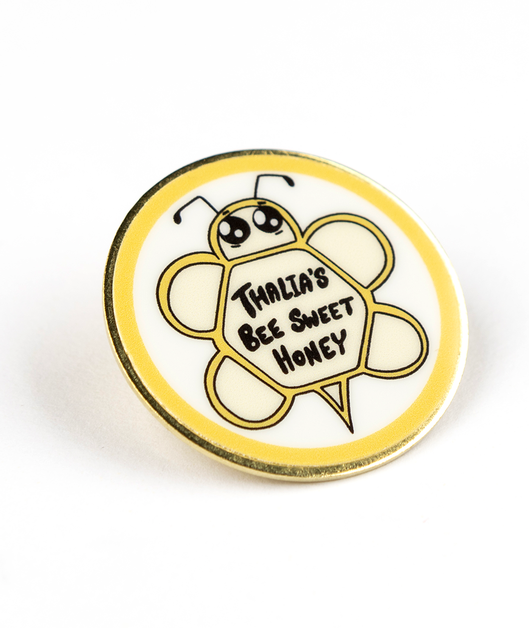 Gold pin with digitally printed geometric bee with large cute eyes and the words Thalia's Bee Sweet Honey on it