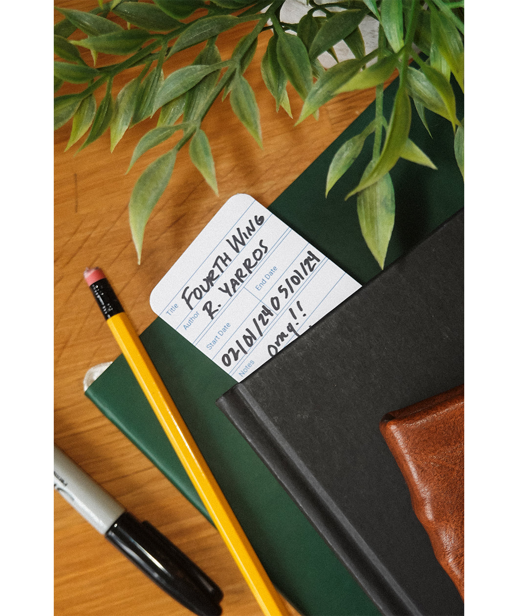 A bookmark that has been written on is placed inside a book atop a desk.