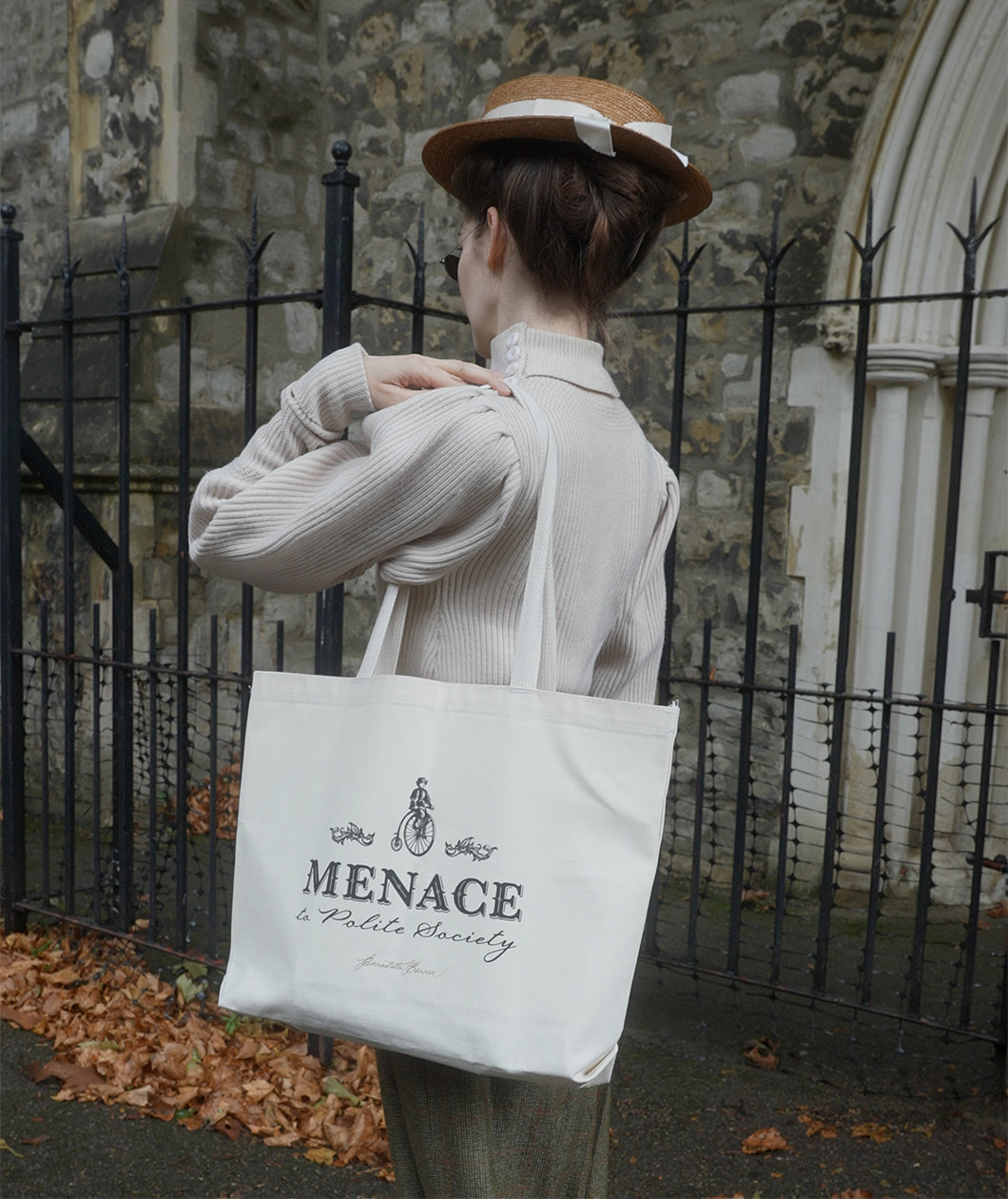 A photograph of Bernadette facing away from the camera showing the Menace to Polite Society tote bag over her shoulder.