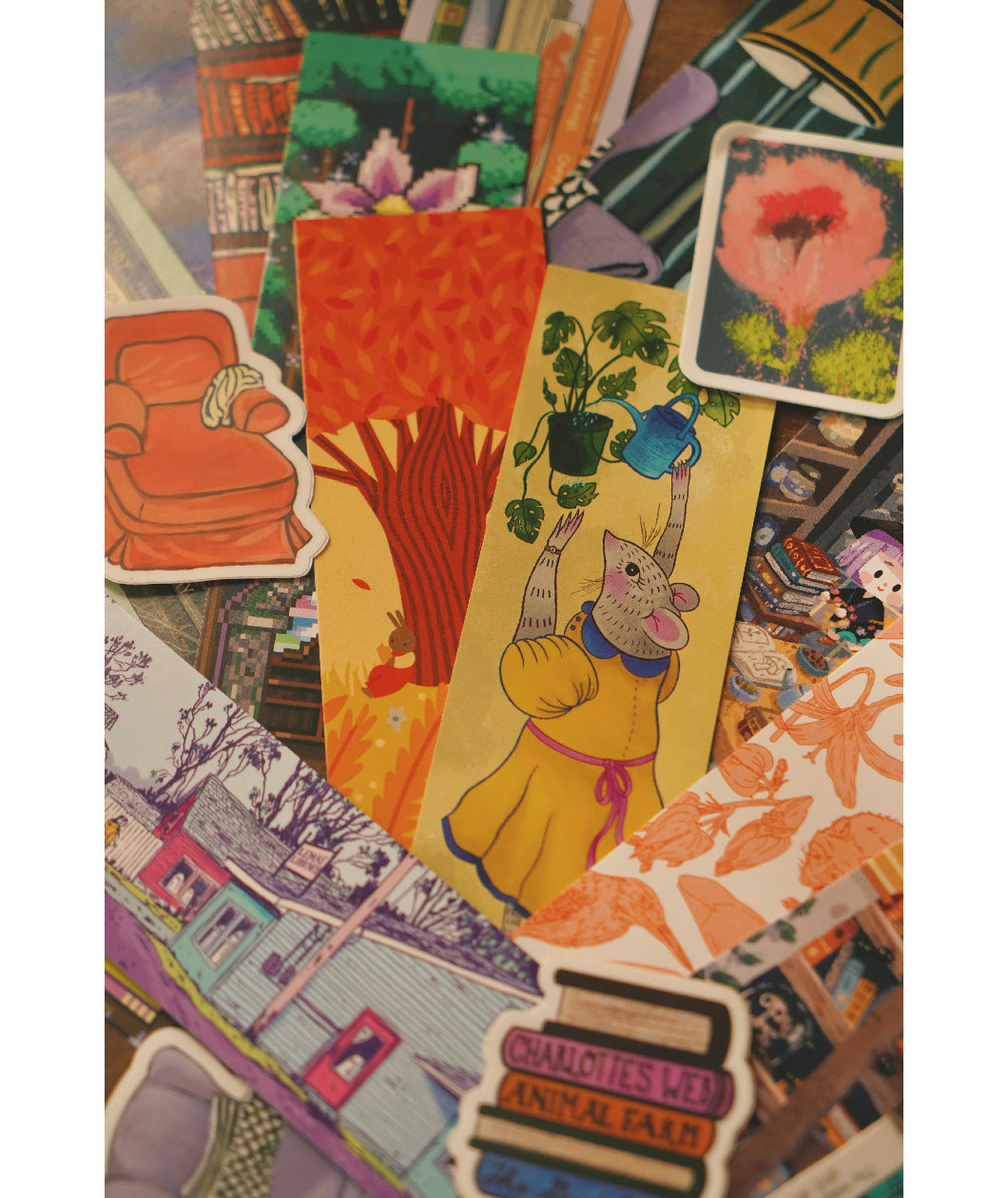 A closeup on an assortment of differently designed paper bookmarks and die cut stickers. From Books Unbound.