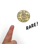 Finger pointing to antique gold coin with words NFTBA in comic sans font engraved into it. There is a clipart picture of a pelican with the phrase Hic sumus pius familia in the center-ish. There is a rope design border. Word RARE! is in this image to show the coin is rare to find.