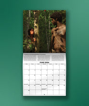 The June page of the Eons 2024 Calendar in front of a green background. The image is two people in a jungle looking at each other.