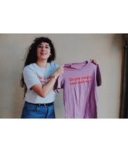 A person wearing an off-white t-shirt with cursive red text across the front that reads "Do you want to read with me?" while holding a purple shirt with the same text on the front. Shirts are from Middlecase.
