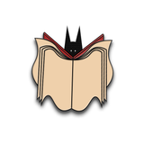 A pin from Re: Dracula of a black bat reading a beige and red book.