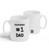 A white mug with a design printed on the front and back. The front has black handwritten text that reads, "Aspiring #1 Dad" and the back has the Semi-Rad logo. From Semi-Rad.