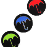 Three circular black pins each with an umbrella on them in a different color: red, blue and bright green. From Bill Wurtz.