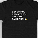 Close-up of black unisex t-shirt with white words "Beautiful Downtown Oakland California" on the center chest - by 99% Invisible