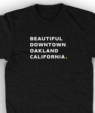 Close-up of black unisex t-shirt with white words "Beautiful Downtown Oakland California" on the center chest - by 99% Invisible