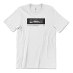 A white t-shirt with a black rectangle in the center with the words "We're figuring it out" written three times in a row with the second line has "figuring" crossed out and the third line has "we're" and "it" crossed out. There is additional small text below this. From Answer in Progress.