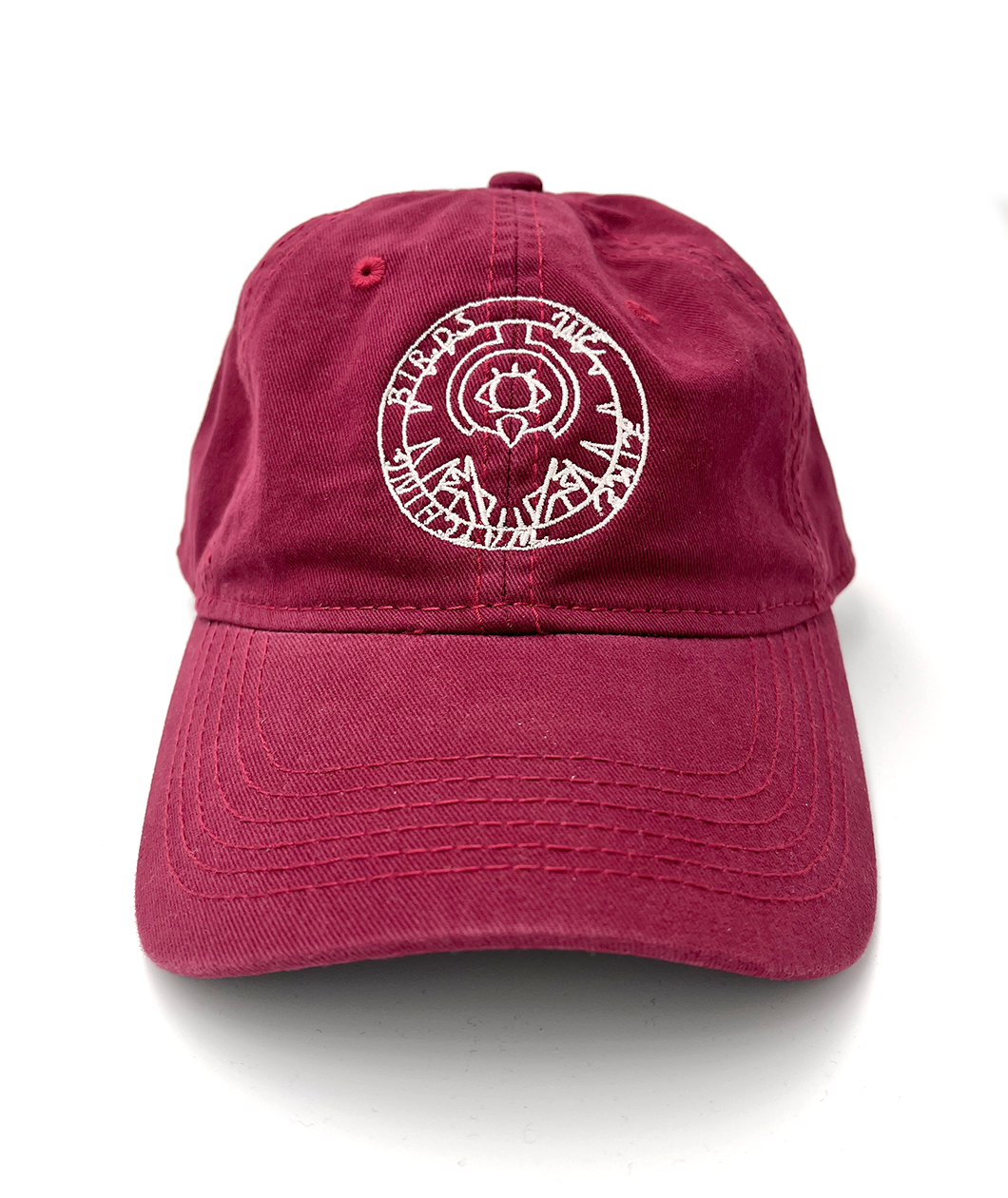 A maroon/red baseball cap with an embroidered circle design on the front in white. From Brian David Gilbert.