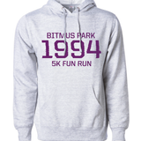 Heather white hoodie with large red 1994 in the front center and "Bitmus Park 5K Fun Run" sandwiched around it in smaller font. The hoodie has a front pocket on the bottom. By Brian David Gilbert 