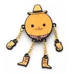 A pumpkin dressed like a cowboy, wearing a cowboy hat and a bandana. Each hand and cowboy boot is connected to the body with a small gold chain. From Brian David Gilbert.