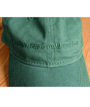 Close up of green ball cap with lowercase embroidered words saying "i wish that i could wear hats". From Brian David Gilbert. 