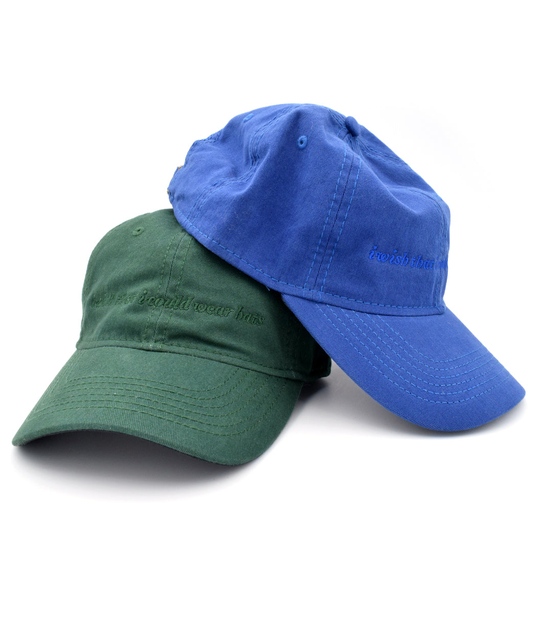 A  blue ball cap stacked on top of a green one. Both with lowercase embroidered words saying "i wish that i could wear hats". From Brian David Gilbert. 
