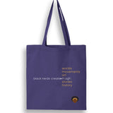 A purple canvas tote bag with text that says "black nerds create" with a list of text on the right that reds "worlds; movements; art; magic; stories; history". On the bottom right hand corner is the Black Nerds Create logo. 