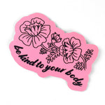 A pink base sticker with a black outline of flowers with a stem attached and some leaves. Underneath, “be kind to your body” is in black cursive font below in a wavy style - from Sierra Schultzzie