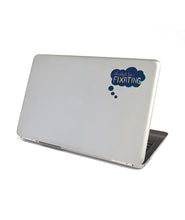 A dark blue thought bubble with a colorful border. The text in the bubble reads "always be...FIXATING" on the back of a silver laptop. From Atypical Artists.