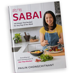 A cookbook title "Sabai" by Pailin Chongchitnant from Hot Thai Kitchen. The cover is Pailin in a kitchen tossing a meal on a plate. 
