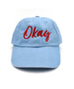 Baby blue hat with “Okay” in red cursive font on front - from It’s Okay To Be Smart