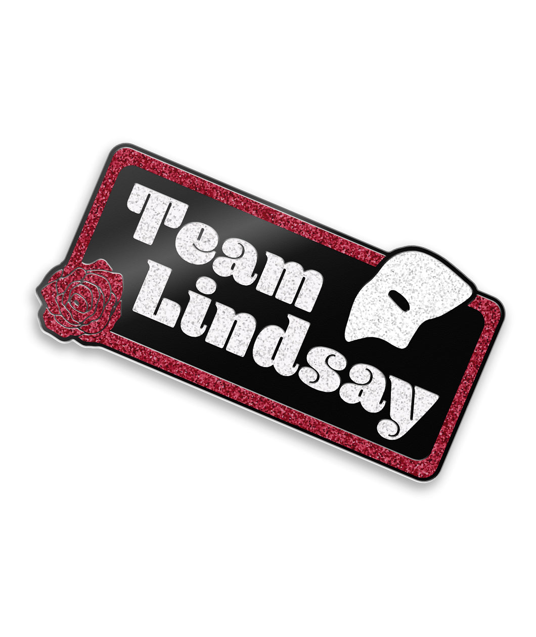 Rectangle pin with curved edges, red glitter outline and black fill. Bottom left of rectangle is a red glitter rose. Top right is half of a white glitter mask. “Team Lindsay” is inside of rectangle in white glitter serif font - from Linsay Ellis. 