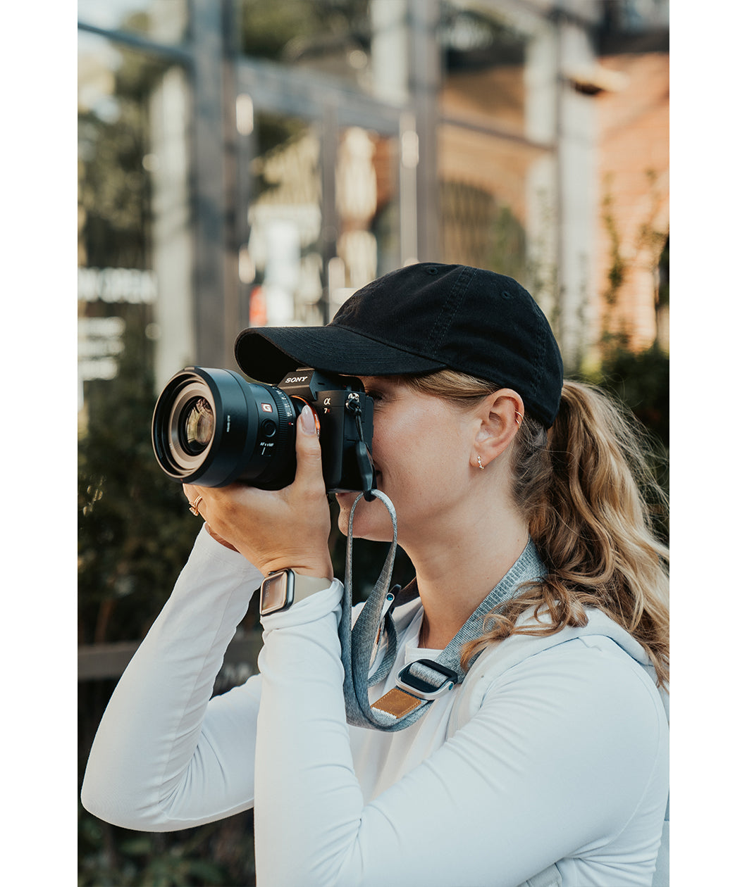 Lizzie Peirce wearing a hat and holding a camera to her face.