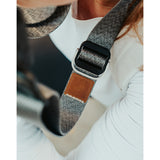 A close up of a grey camera strap with a brown leather square that has a "LP" etched into it for Lizzie Peirce.